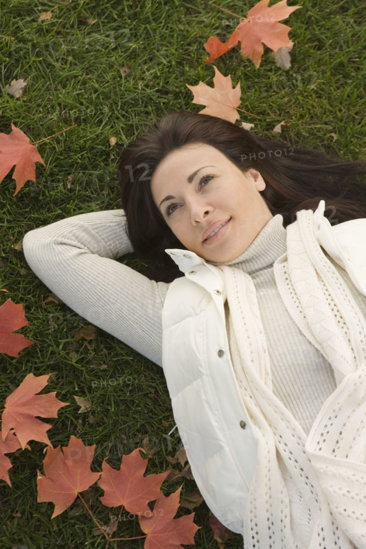 Woman lying on grass on fall day.