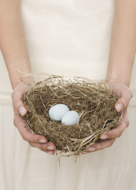 Female holding nest with eggs.