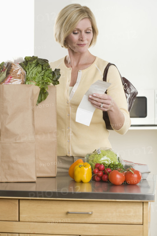 Woman checking grocery receipt.