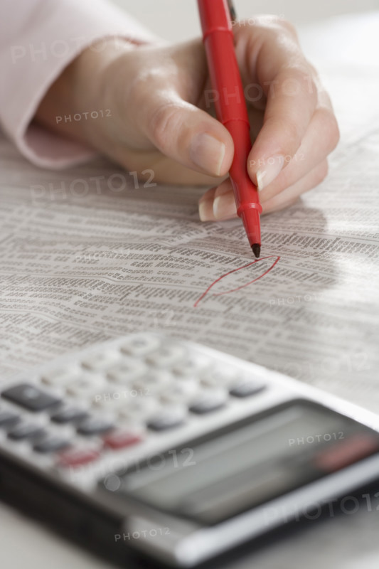 Woman checking financial page with calculator.