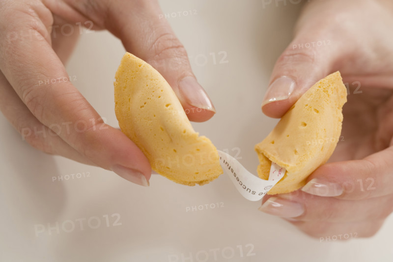 Woman breaking fortune cookie.