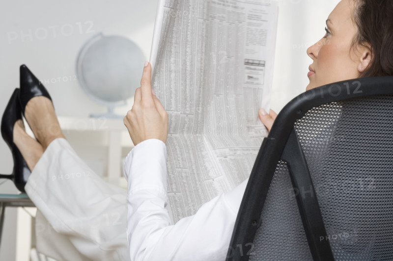 Woman reading newspaper business page.