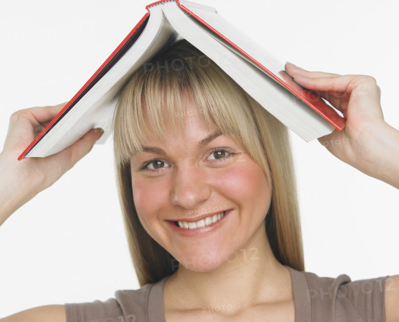 Studio shot of woman holding a book over her head.