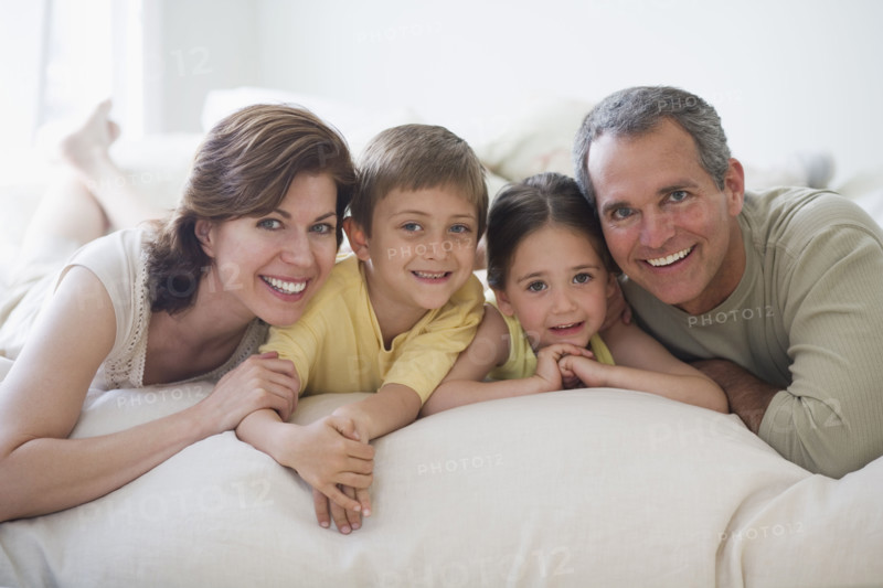 Family lying on bed.