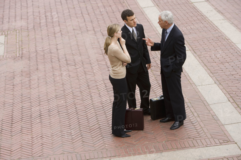 Three business people talking outdoors.