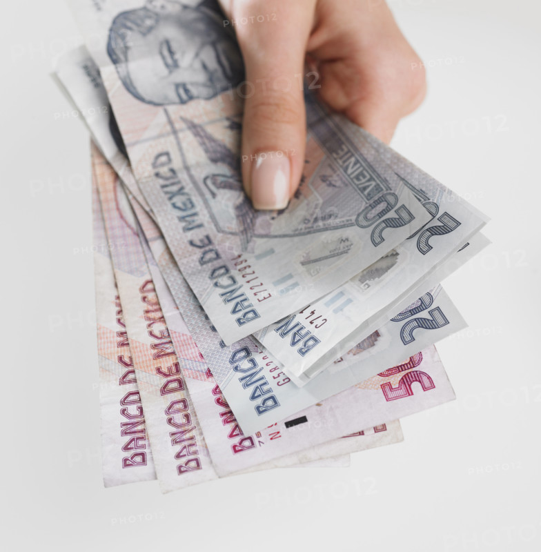 Close up studio shot of woman's hand holding Mexican money.