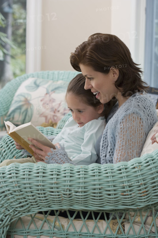 Mother reading to young daughter .