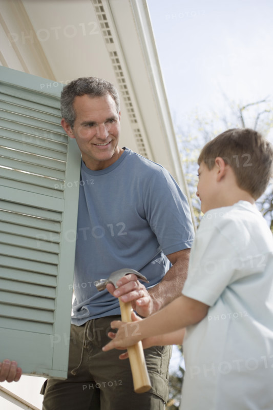 Father and young son fixing shutters.