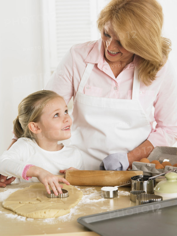 Grandmother and young granddaughter making cookies.