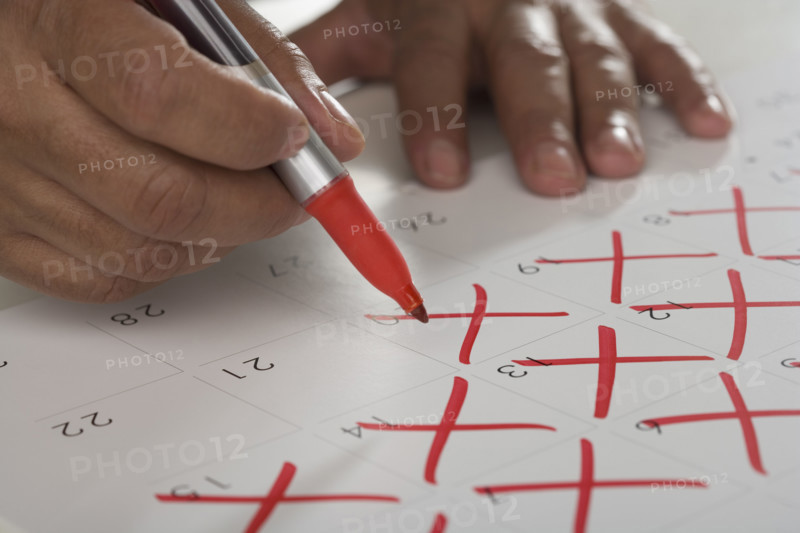Close up of man crossing out days on calendar.