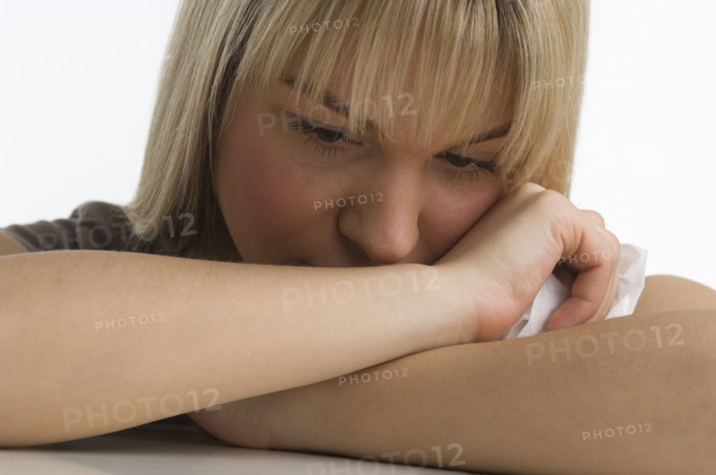 Sad woman with chin resting on her arms.