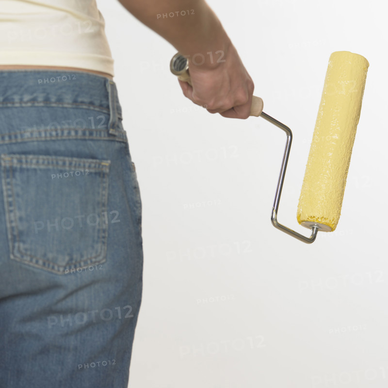 Rearview of woman holding paint roller.