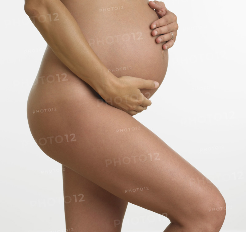 Studio shot of nude pregnant woman holding stomach.