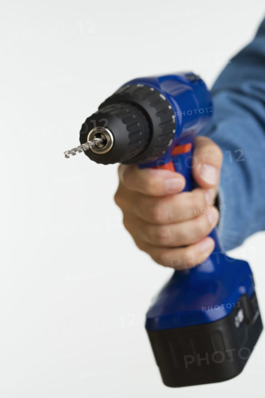 Close up studio shot of man holding cordless drill.