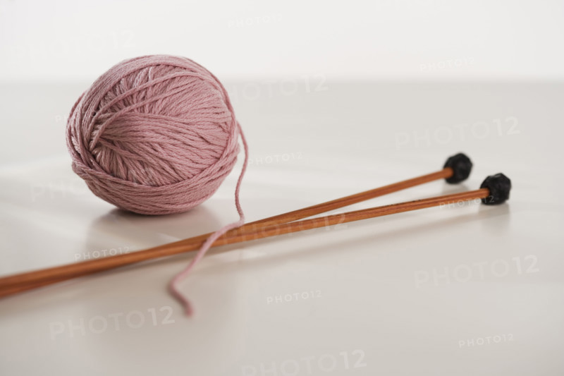 Close up studio shot of ball of yarn and knitting needles.