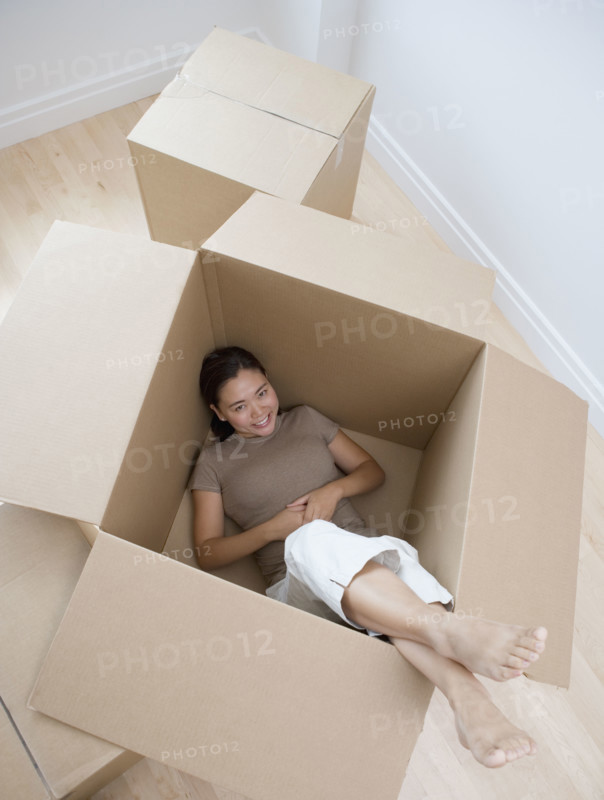 Woman sitting in empty moving box.