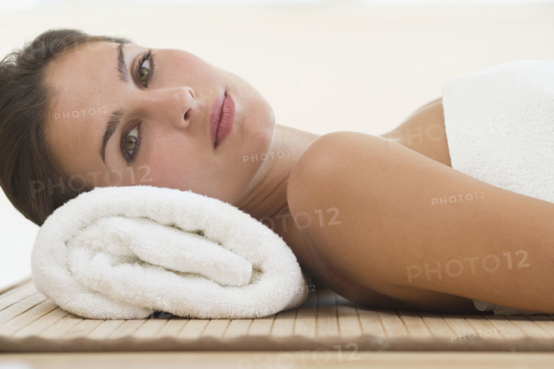 Woman laying on mat with rolled towel under neck.