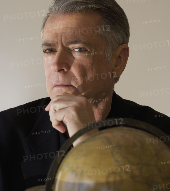Senior businessman next to globe.