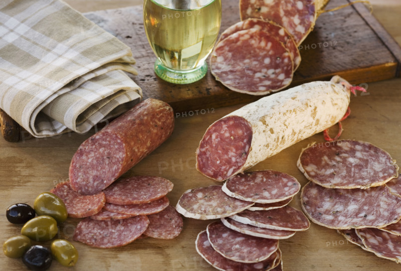 Sliced sausages and olives on table.