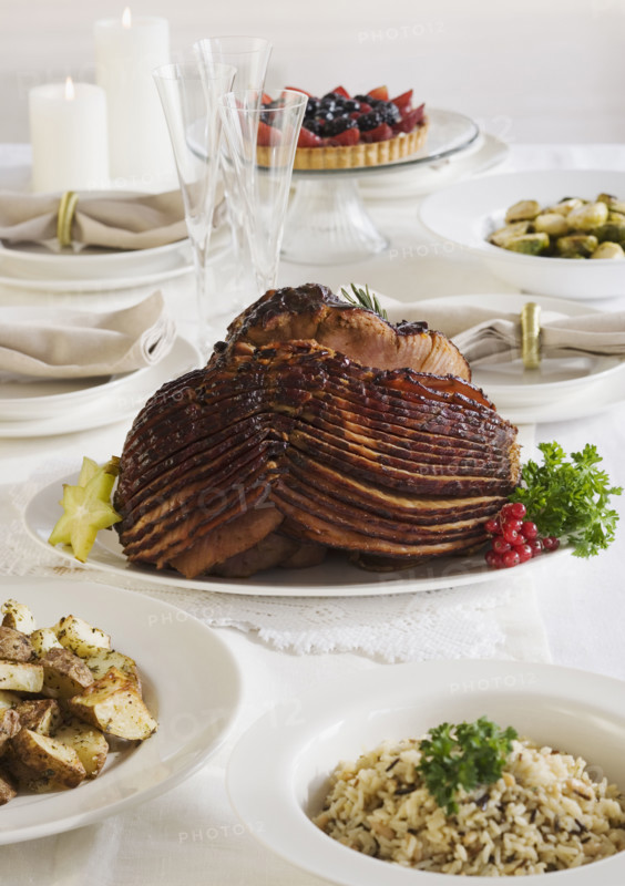 Spiral ham and side dishes on set table.