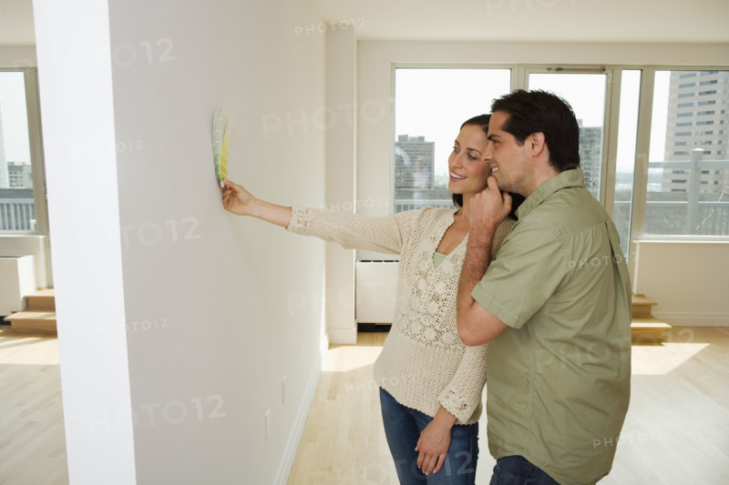 Couple holding paint swatches up to wall.