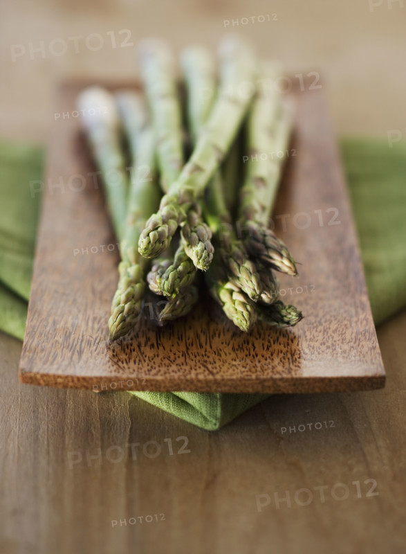 Close up of asparagus on wooden plate.