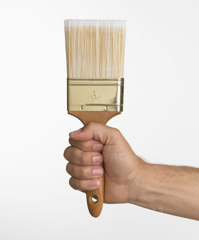 Close up studio shot of man holding paintbrush.