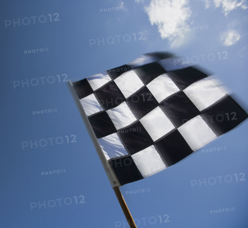 Checkered flag waving under blue sky.