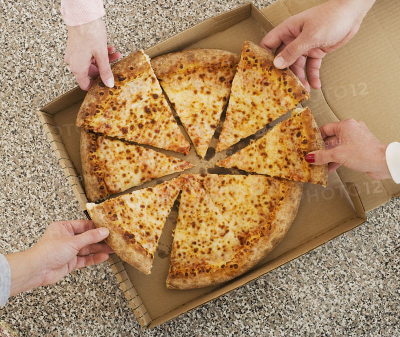 People talking slices of pizza from box.