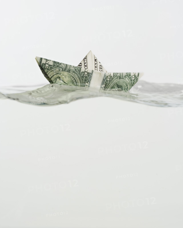 Boat made of US dollar floating on water.