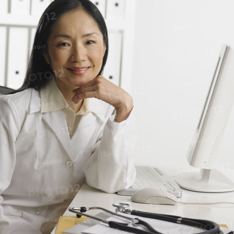 Female doctor sitting at computer smiling.