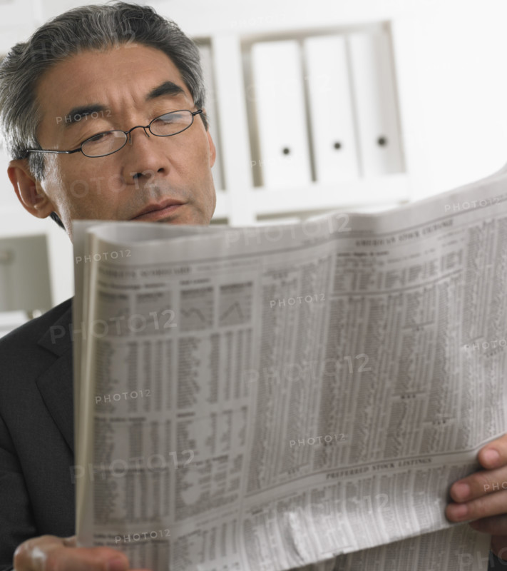 Senior Asian businessman reading newspaper.