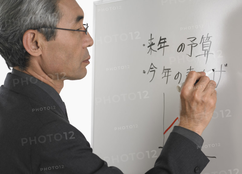 Senior Asian businessman writing on white board.