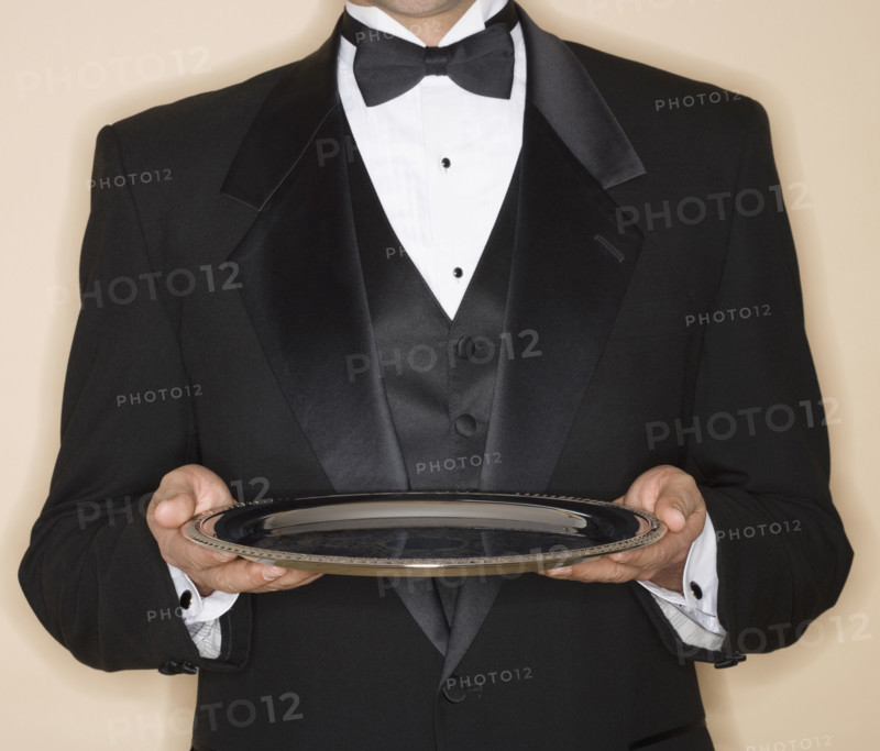 Waiter in tuxedo holding silver platter.