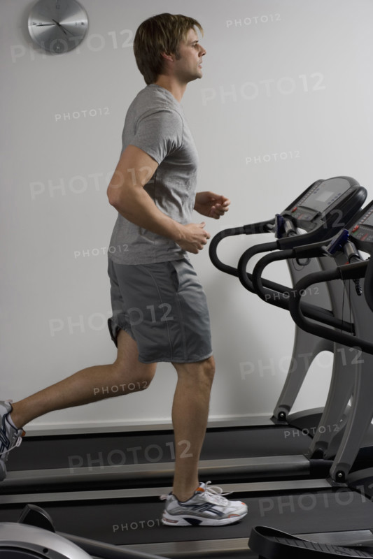 Man running on treadmill at health club.