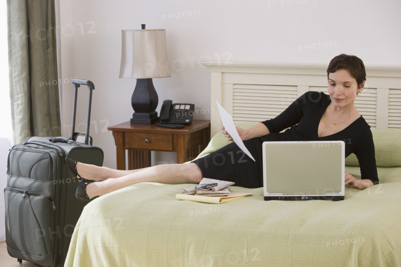 Businesswoman working on bed in hotel room.