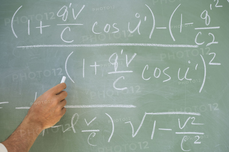 Professor writing formulae on blackboard.