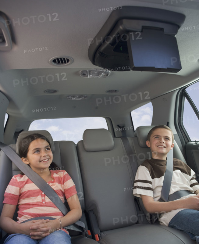Brother and sister watching moving in car.