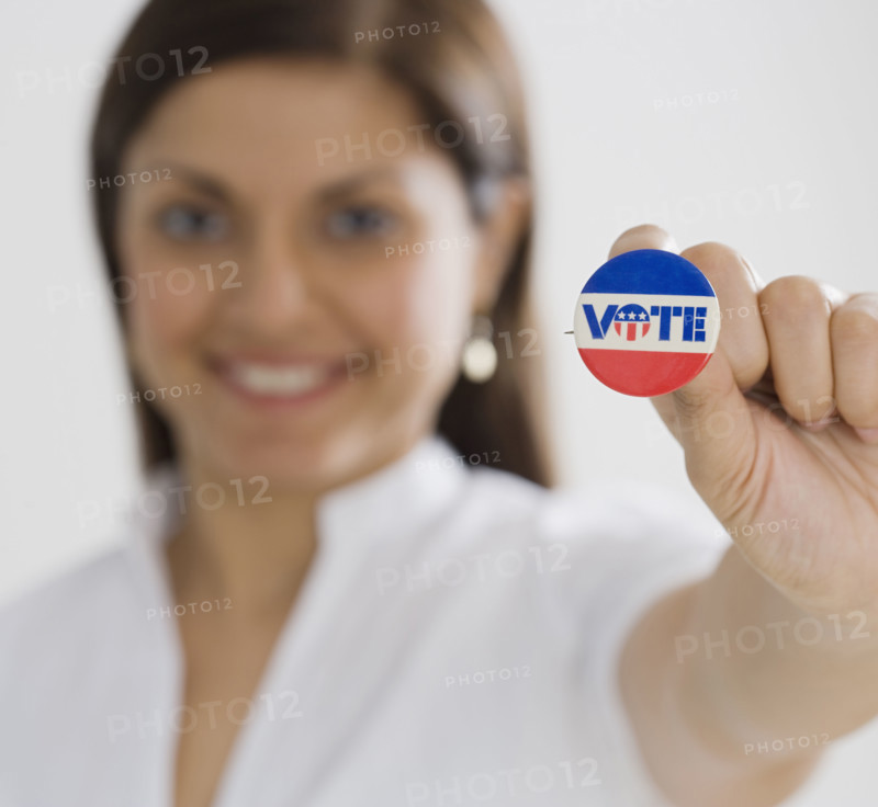 Indian woman holding up Vote pin.