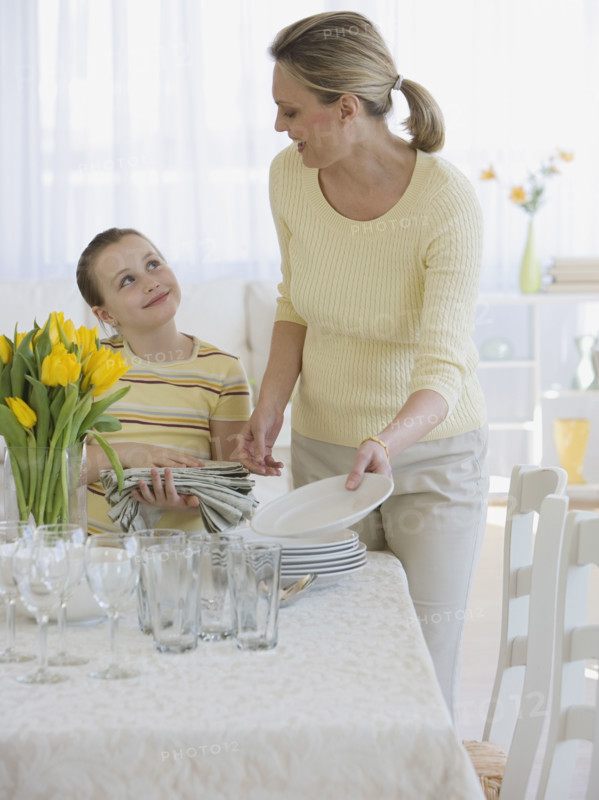 Mother and daughter setting table.