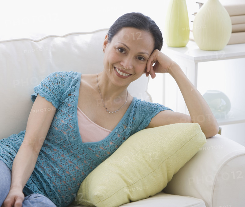 Asian woman sitting on sofa.
