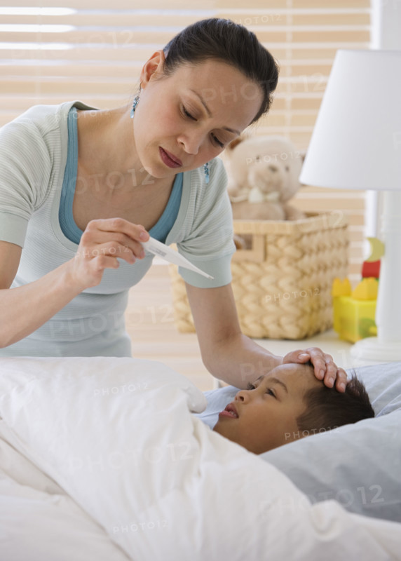 Asian mother taking son’s temperature.
