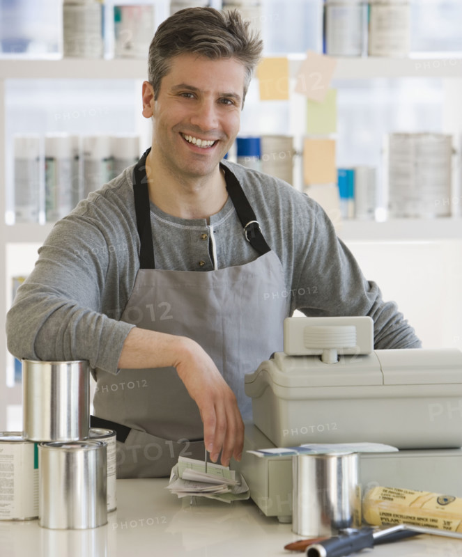 Male clerk at counter of paint store.
