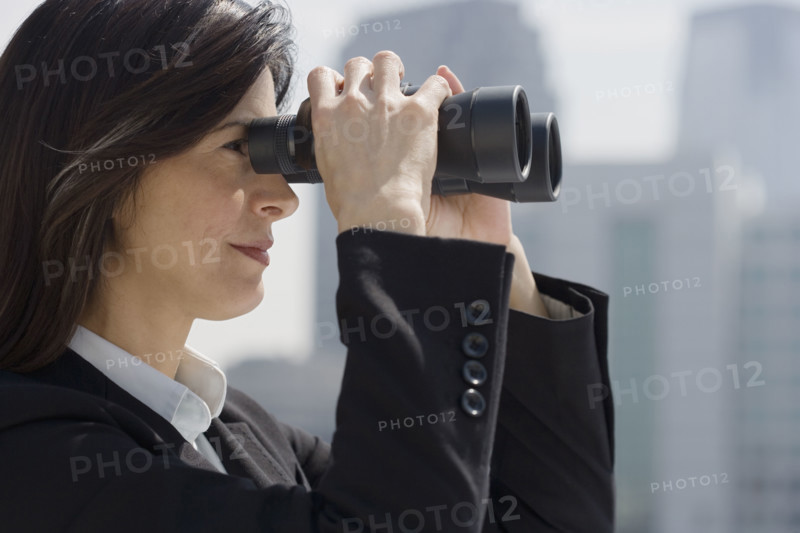 Businesswoman looking through binoculars.