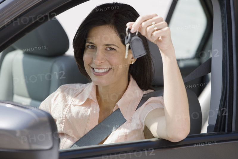 Woman holding car keys in car.