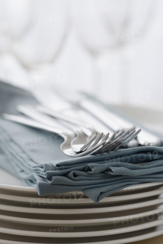 Stack of plates, silverware and napkins.