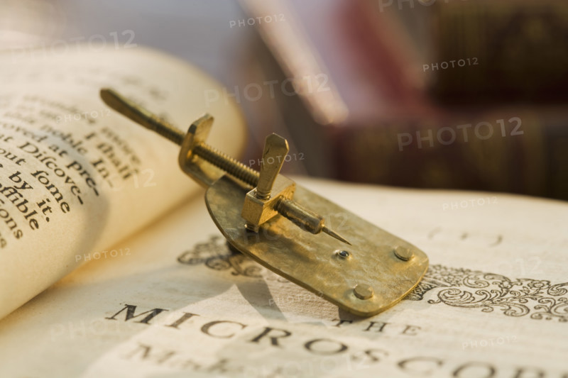 Model of Leeuwenhoek microscope on book.