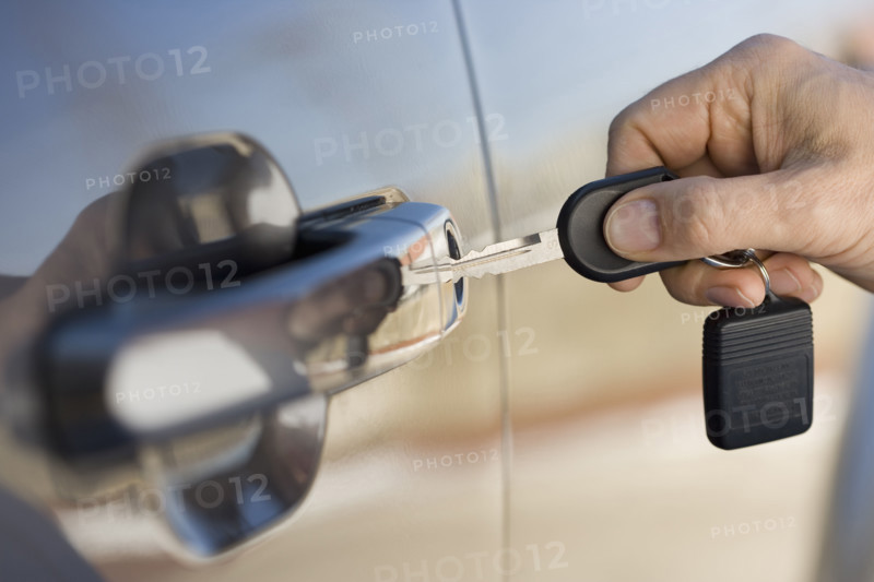 Man putting car key in door.