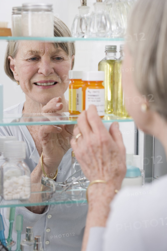 Senior woman looking in medicine cabinet.