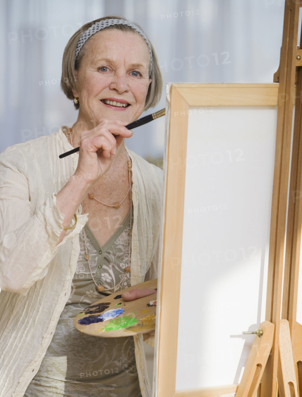 Senior woman painting on easel.